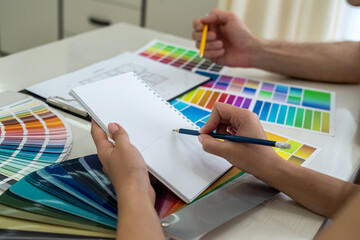 Creative designers making some notes about new project in notebook