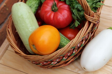 Basket with tomatoes, cucumbers, eggplants and zucchini