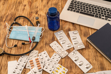Fototapeta na wymiar on a wooden table is a laptop, pills, stethoscope, notebook and mask. Medicine concept