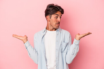 Young mixed race man isolated on white background confused and doubtful shrugging shoulders to hold...