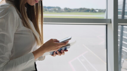 Fototapeta premium Close up of business woman's hands using smartphone send text messages at the gate of the airport terminal while waiting for the flight, mobile phone checks emails, business trips, mobile phone.