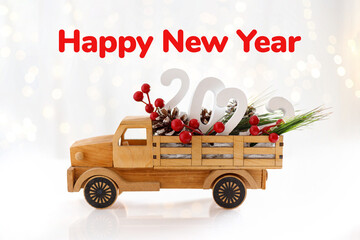 Happy New Year 2022. Wooden toy car with with berries and cones. Creative concept for new year greeting card. Happy new year text.