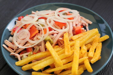 a plate of fresh sausage salad and french fries 