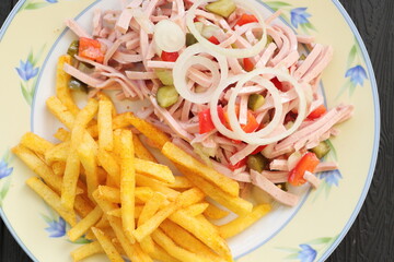 a plate of fresh sausage salad and french fries 