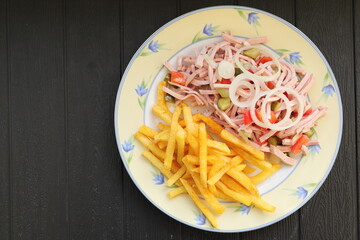 a plate of fresh sausage salad and french fries 
