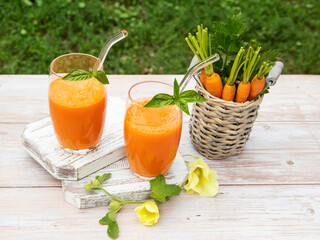 Fresh squeezed smoothie  carrot juice in a two glass. Healthy eating, detox, dieting. Outside