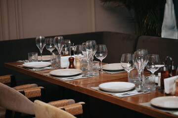 Beautiful table set in elegant restaurant with glass of wine, glass of water, knife, spoon and fork, cutlery, ready to welcome customers.