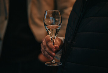 Elegant waiter pours champagne from bottle into glass at restaurant. Sommelier tasting white...