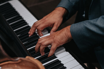 Obraz premium The hands of a musician playing the piano closeup in dark tones. Good for posters or media posts.