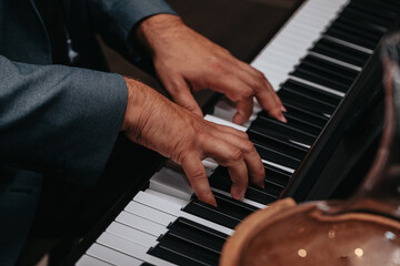 Fototapeta premium The hands of a musician playing the piano closeup in dark tones. Good for posters or media posts.