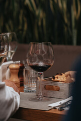 Elegant waiter pours red wine from bottle into glass at restaurant. Sommelier tasting wine in restaurant. Copy space for text menu elegant or recipe on dark background.