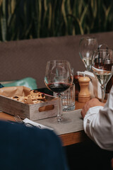 Elegant waiter pours red wine from bottle into glass at restaurant. Sommelier tasting wine in restaurant. Copy space for text menu elegant or recipe on dark background.