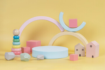 Composition of colorful educational natural wooden toys and geometric shape podium, platform on pastel yellow background. Front view