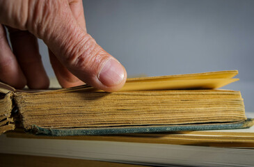 Caucasian man turning old aged book pages , focus on the thumb, space for text.