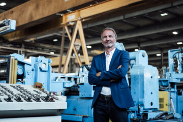 Male business professional standing with arms crossed at metal industry
