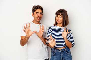 Young mixed race couple isolated on white background rejecting someone showing a gesture of disgust.