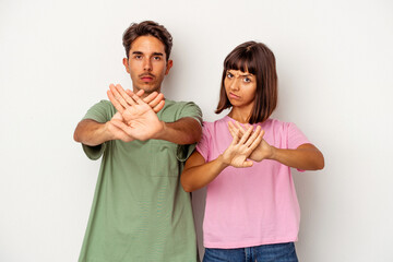 Young mixed race couple isolated on white background standing with outstretched hand showing stop sign, preventing you.