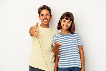 Fototapeta premium Young mixed race couple isolated on white background stretching hand at camera in greeting gesture.