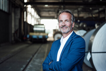 Senior businessman with arms crossed standing at distribution warehouse