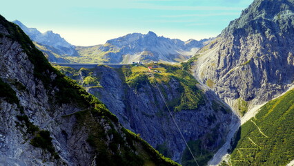 Fototapeta na wymiar Gebirge mit Staumauer des Lünersees mit Seilbahn und Wanderweg zur Douglasshütte von unten gesehen