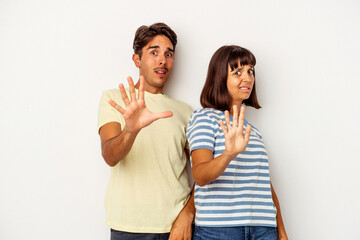 Young mixed race couple isolated on white background being shocked due to an imminent danger