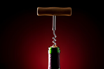 Wine bottle and wine opener on black background with red backlight