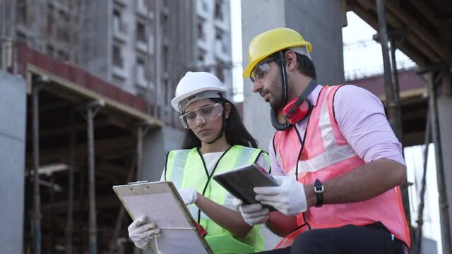 Two Indian man and woman Civil Engineers work at Construction Site outdoor.Two Asian worker checking work details and discussing with site plans.civil engineers doing a survey on a construction site.