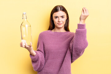 young hispanic woman making capice or money gesture, telling you to pay. water bottle concept