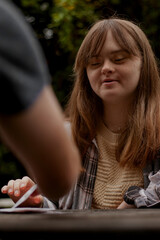 Young woman with Down Syndrome playing cards outdoors and looking confident