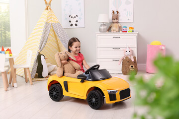 Adorable child with toy driving car in room at home