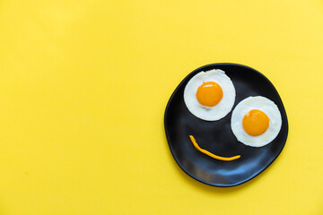 Two eggs in the black plate on yellow background
