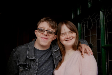 Young couple with Down Syndrome and Foetal Alcohol Syndrome standing at front door and smiling