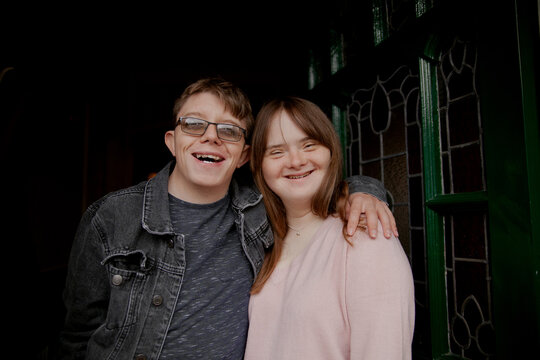 Young couple with Down Syndrome and Foetal Alcohol Syndrome standing at front door and smiling