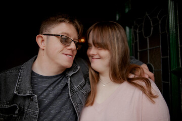 Young couple with Down Syndrome and Foetal Alcohol Syndrome standing at front door looking at each...