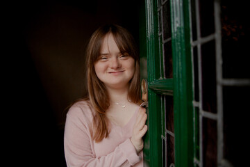 Young woman with Down Syndrome opening door and smiling