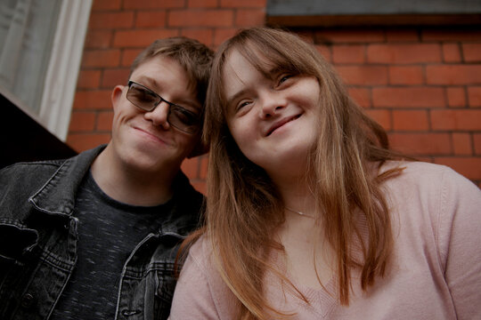 Young couple with Down Syndrome and Foetal Alcohol Syndrome sitting on front door steps and having fun