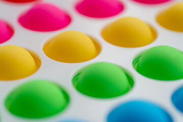 Children's sensory toy pop it close-up colored rainbow bumps on white