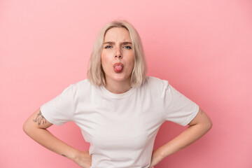 Young caucasian woman isolated on pink background funny and friendly sticking out tongue.