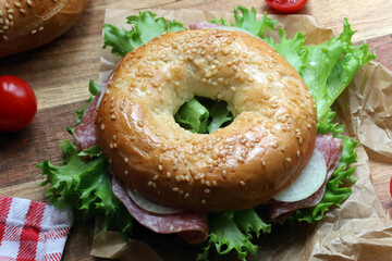 Seeded bagel filled with salad, onions, tomatoes and salami