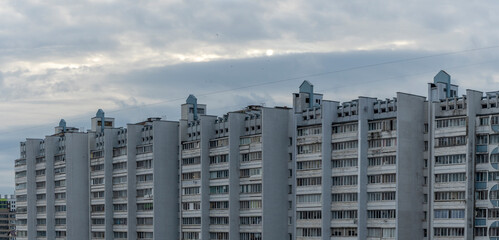 Fototapeta premium Bottom view of a multi-storey panel residential building on dramatic sky background. City life view.