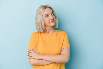 Young caucasian woman isolated on blue background dreaming of achieving goals and purposes