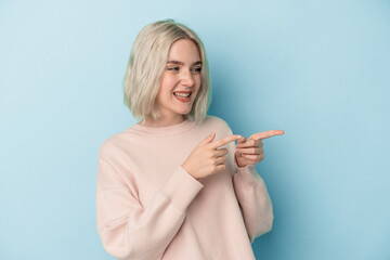 Young caucasian woman isolated on blue background points with thumb finger away, laughing and carefree.