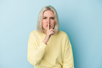 Young caucasian woman isolated on blue background keeping a secret or asking for silence.