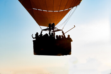 Close up of a group of people riding in a hot air balloon in the foreground and backlighting