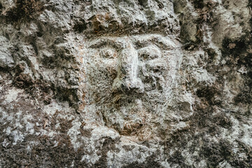 The mystical face of an ancient screaming deity carved in the rock. The concept of myth and...