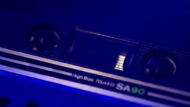 Closeup of audio casssette rolls in neon lights