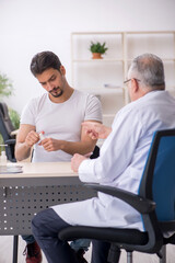 Obraz premium Old male doctor suggesting pills to young male patient