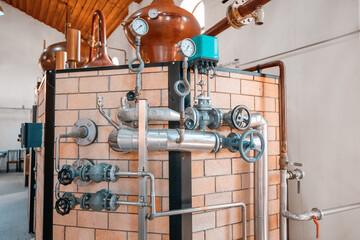 At the distillery plant of strong alcohol. Close-up of pipes with valves and a pressure gauge