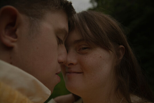 Face to face portrait of young couple with Down Syndrome and Foetal Alcohol Syndrome looking confident and touching noses