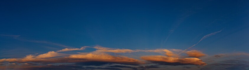 Panorama of clouds illuminated by the setting evening sun